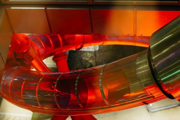Helix, the world's tallest and longest tunnel slide lit up in bright red lighting at night for a Halloween event