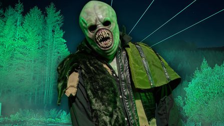 A bald-headed monster with a round mouth full of rows of sharp teeth stands before an eerily-illuminated zip line and forest.