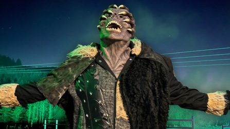 A monster with two claws wrapped around its head stands with outstretched arms in front of a zip line at night, illuminated by atmospheric green light.