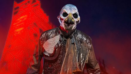 A bird-like monster with blackened eyes stands menacingly in front of a tower mining structure, illuminated by eerie red lights